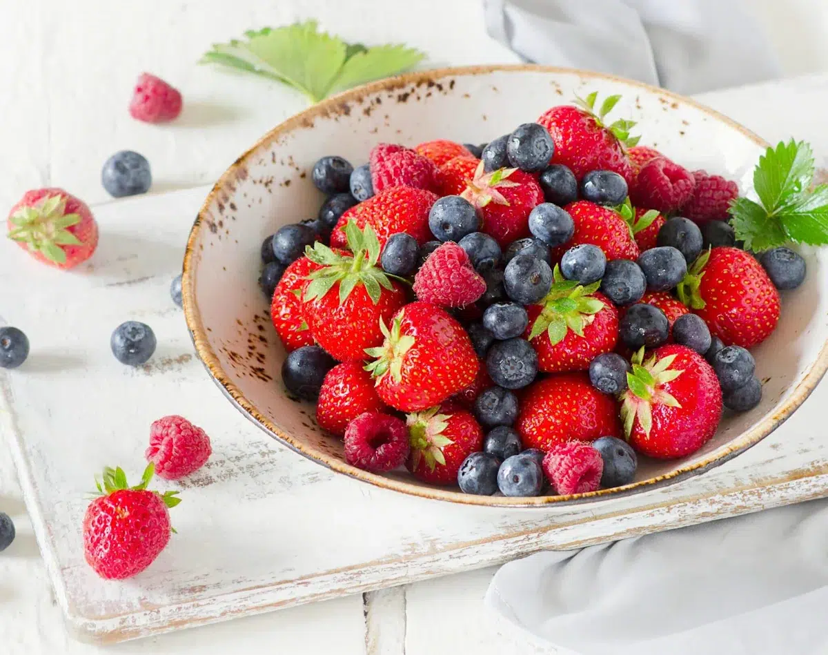 Eine weiße Schüssel mit Erdbeeren, Heidelbeeren und Himbeeren.