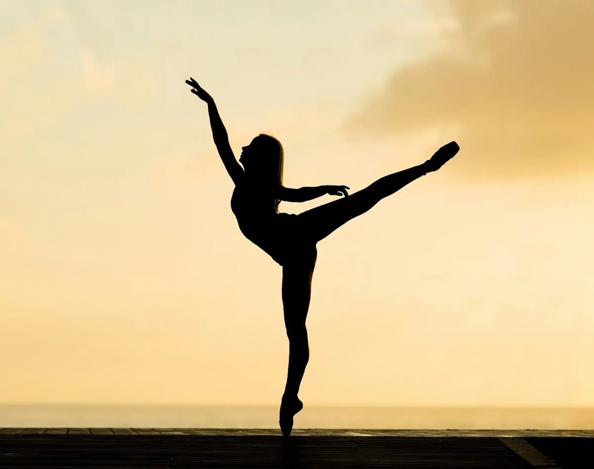 Posierende Balletttänzerin bei Sonnenuntergang am Strand.