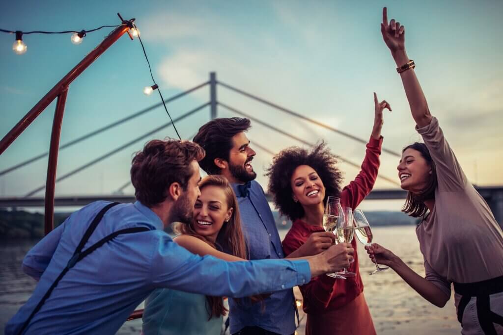 Fünf Freunde feiern mit einem Glas Sekt in der Hand. Sie lachen und haben Spaß.