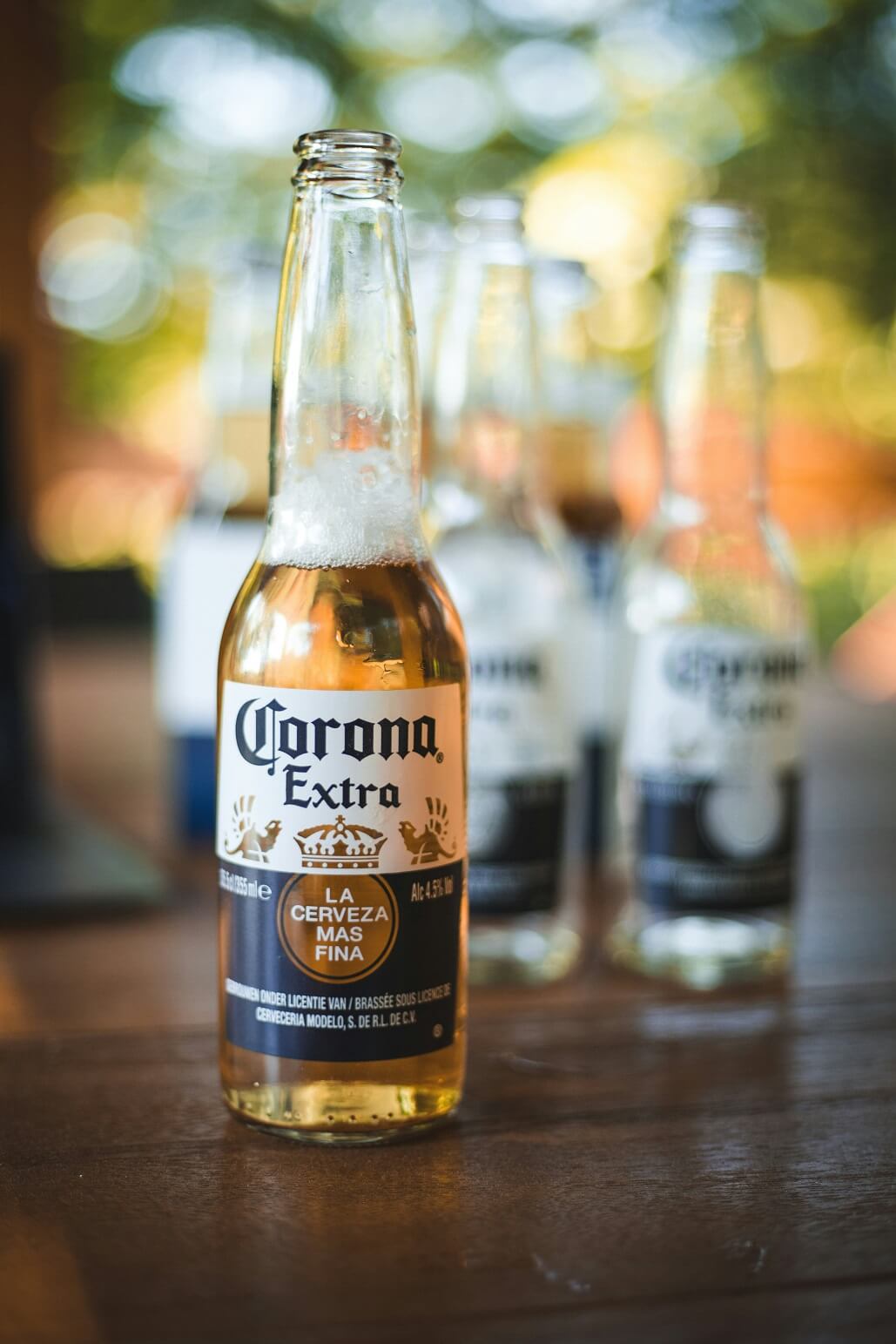 Auf dem Tisch steht eine Flasche Corona. Im Hintergrund stehen ein paar weitere bereits leere Flaschen Corona.