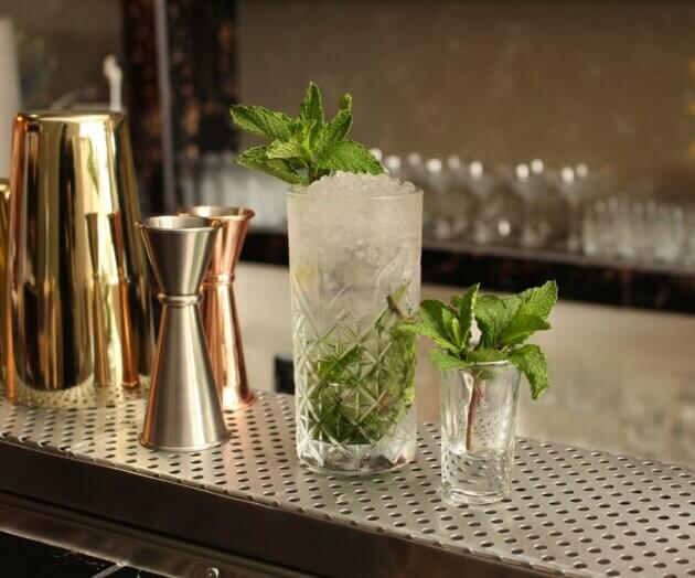 Auf dem Barthresen steht ein Mojito garniert mit frischer Minze.