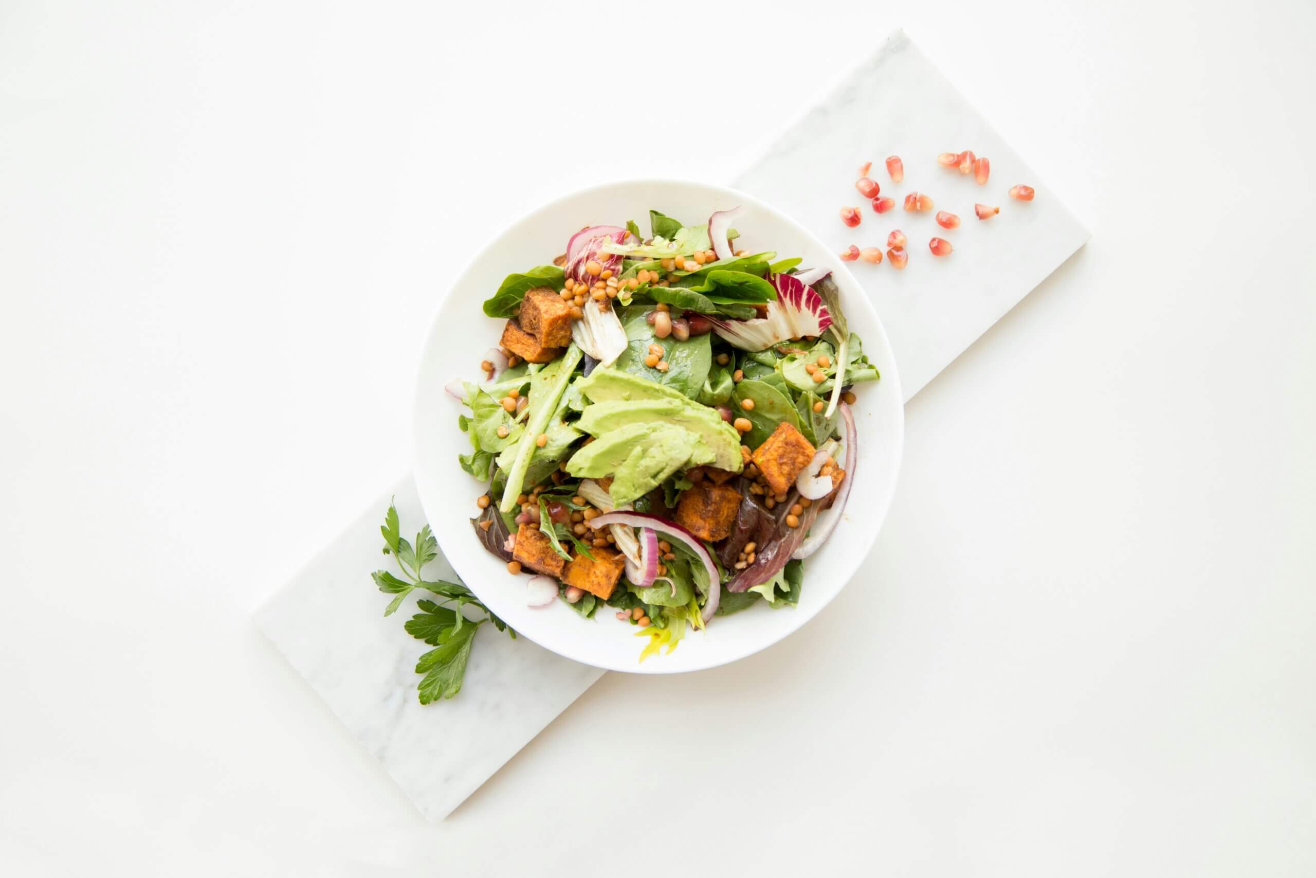 Bunte Bowl mit grünen Salat, Avocado, Tofu und Zwiebel