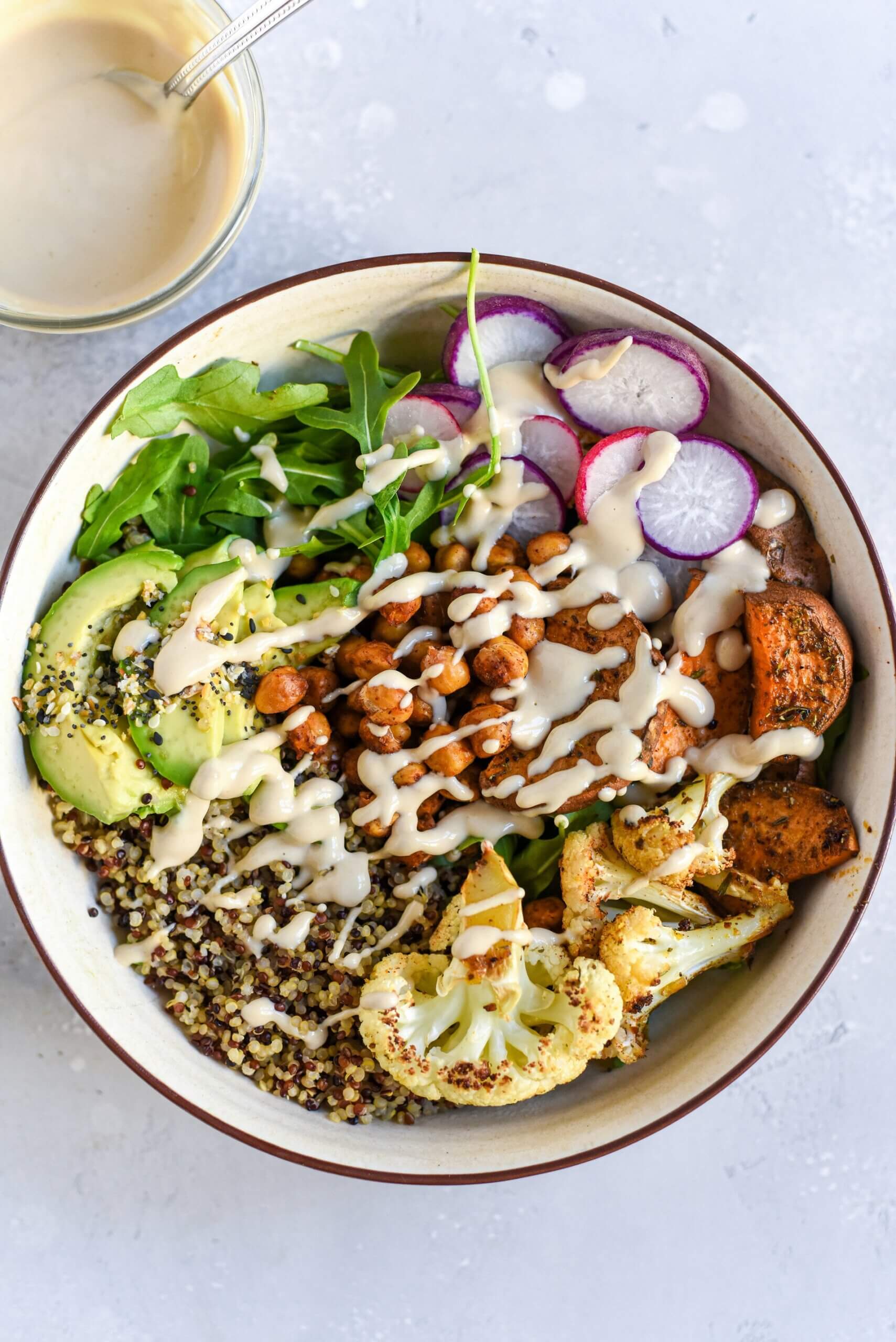 Bowl mit Quinoa, Ruccola, Radieschen, Kichererbsen, Avocado und Süßkartoffeln.