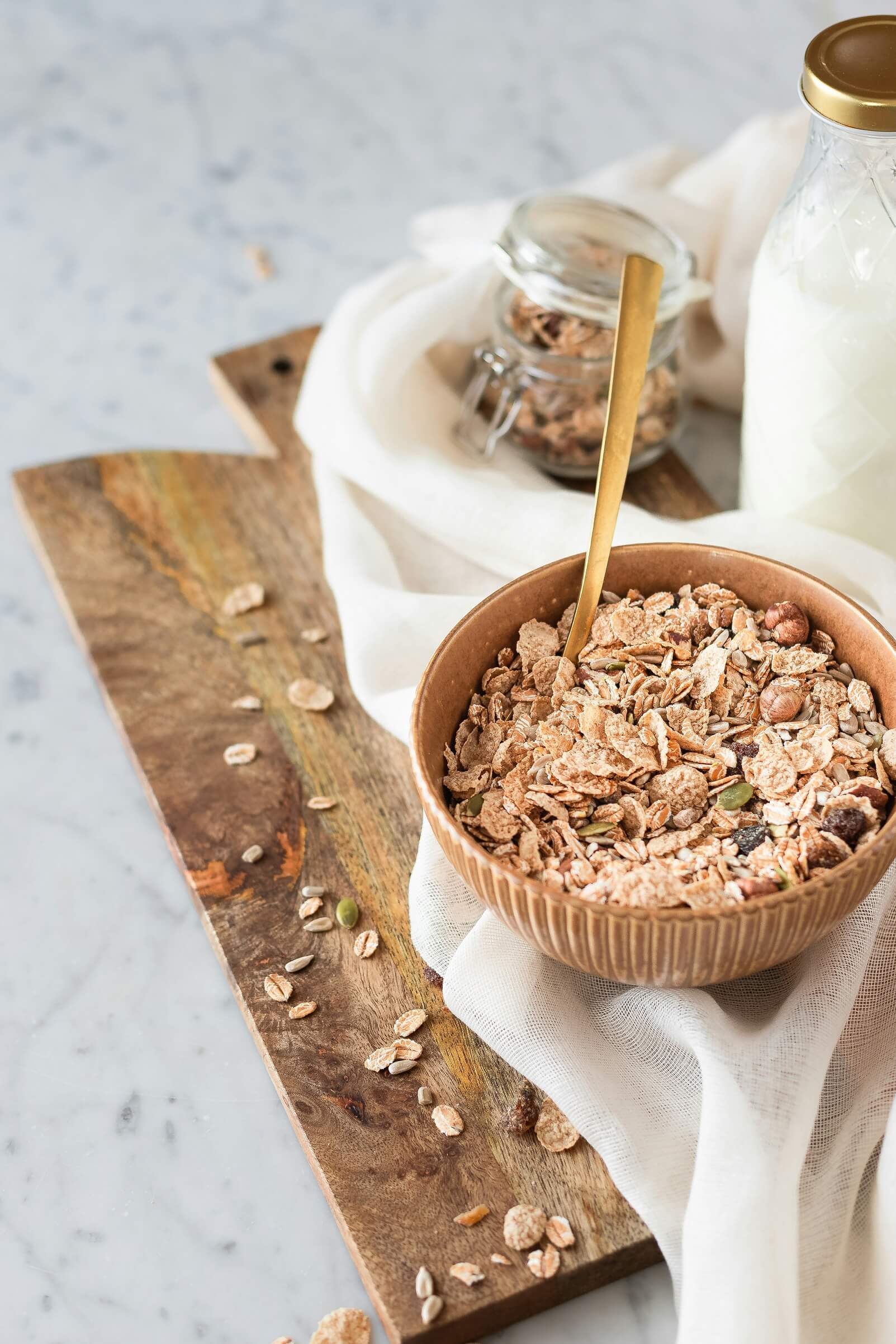 Eine Schale mit Haferflocken und Müsli. Daneben steht eine Flasche pflanzliche Milch.