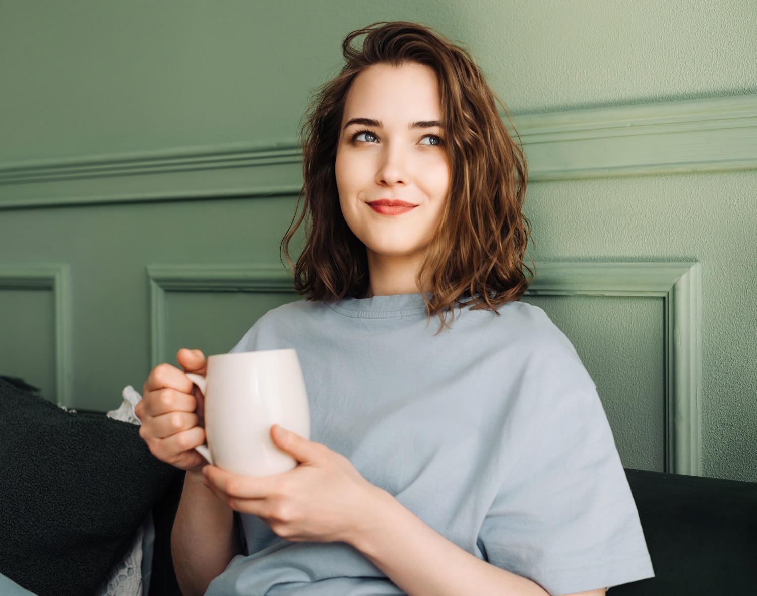 RINGANA Darmkur: Frau die auf einer Couch sitzt mit einer Tasse Tee in der Hand.
